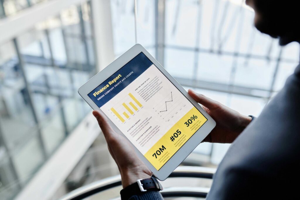 Person holding a tablet that shows a finance report with charts and yellow highlight sections in the screen display.