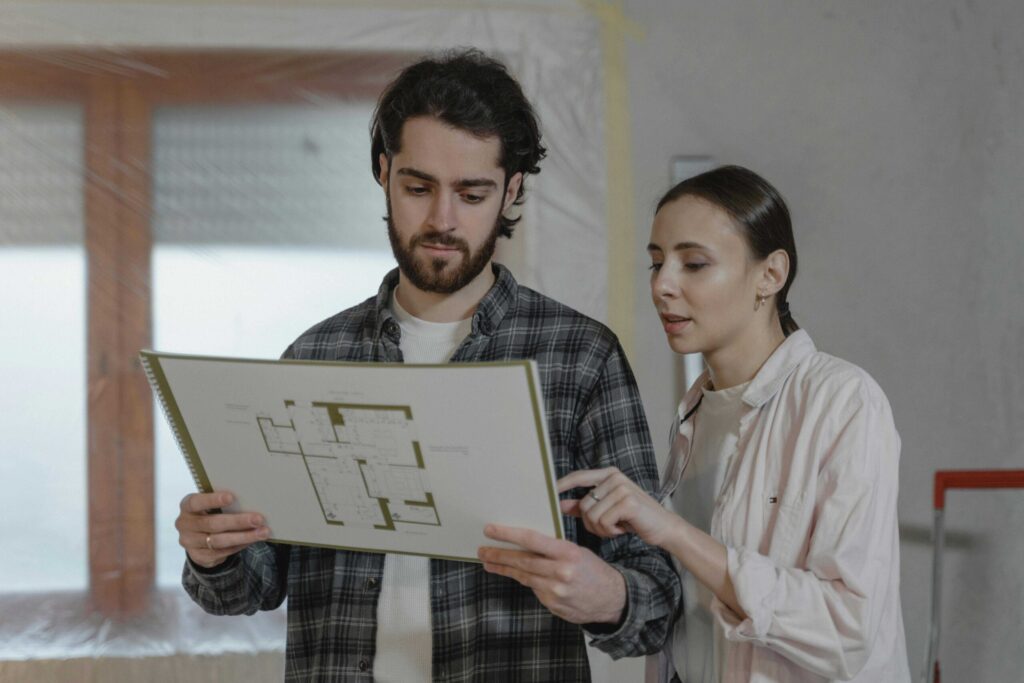 Two people review a large architectural blueprint together indoors