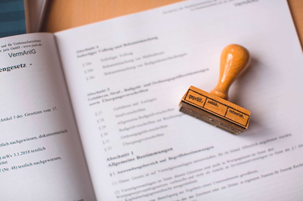 Close-up of a wooden rubber stamp resting on an open book page with German text visible in the background.