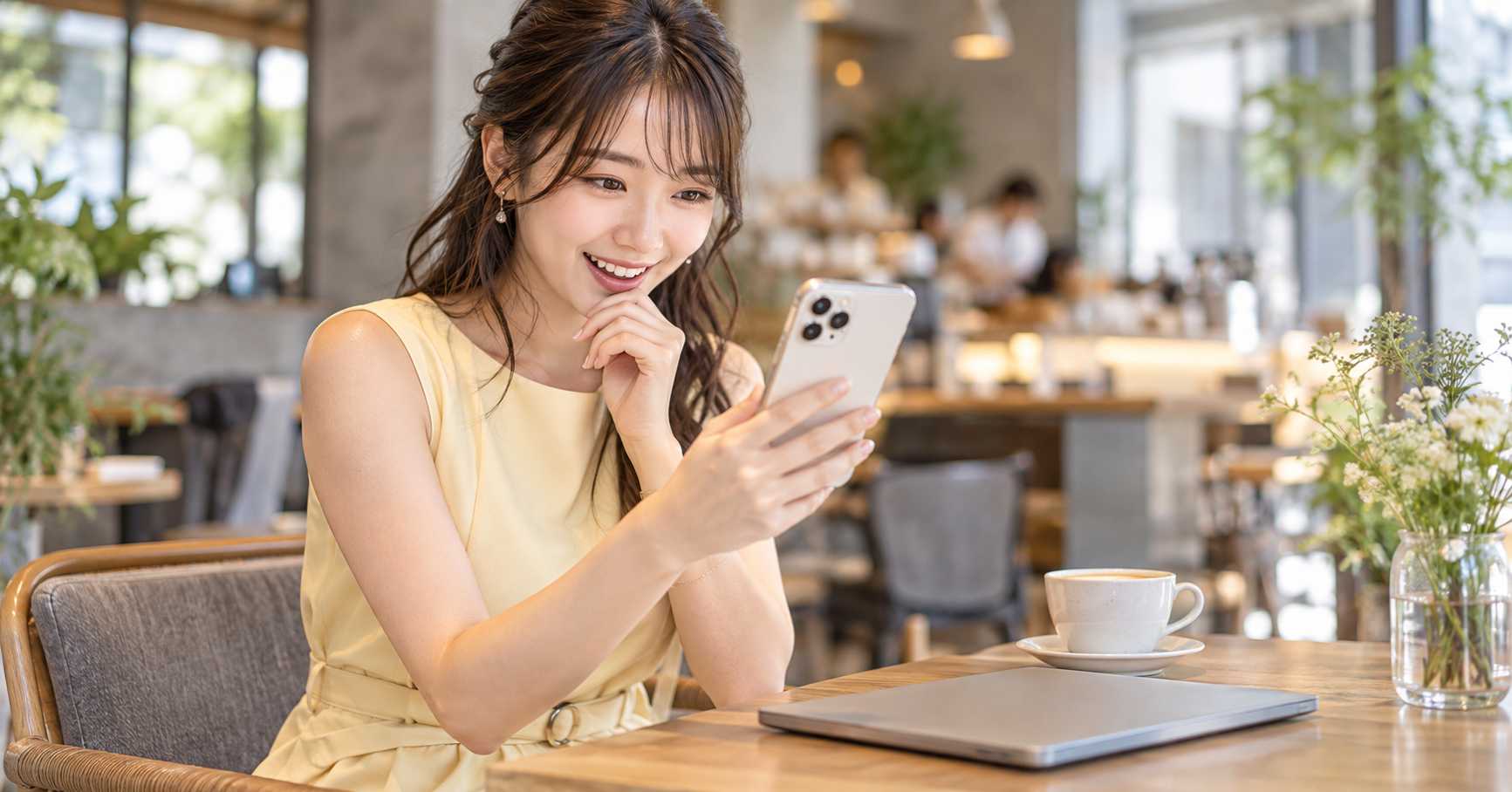 カフェでスマートフォンを見ながら微笑む女性